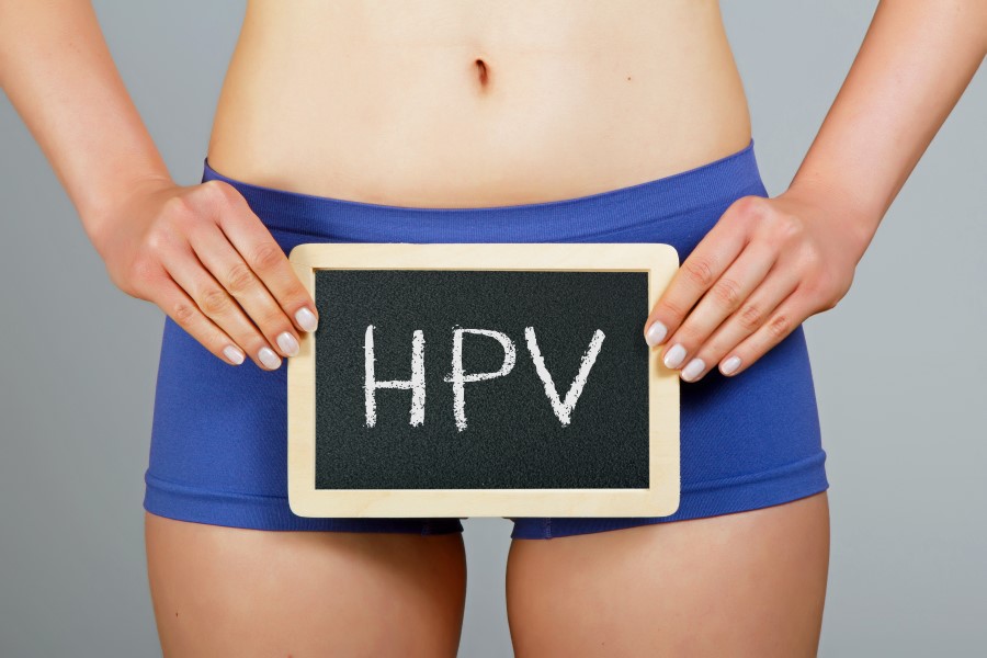 Kobieta w bieliźnie, na wysokości bioder trzyma niewielką tablicę kredową z napisem HPV.