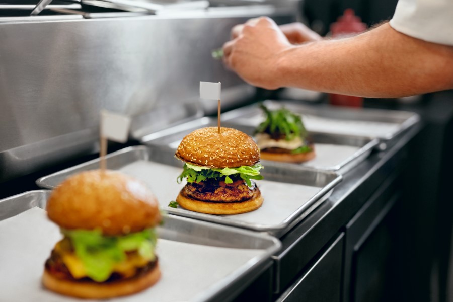 Kucharz przygotowuje popularny fast food - hamburgery.