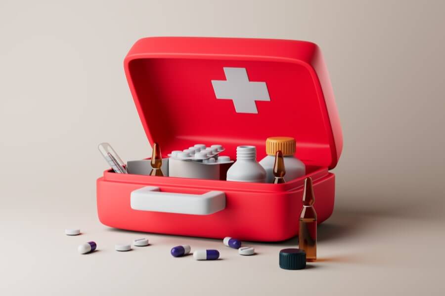 Czerwona apteczka zawierająca blistry leków, buteleczki i ampułki.