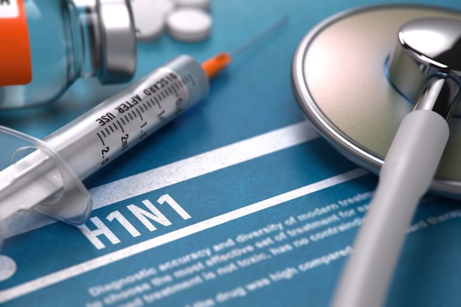 Strzykawka i stetoskop na niebieskiej kartce z napisem H1N1 (wirus świńskiej grypy).