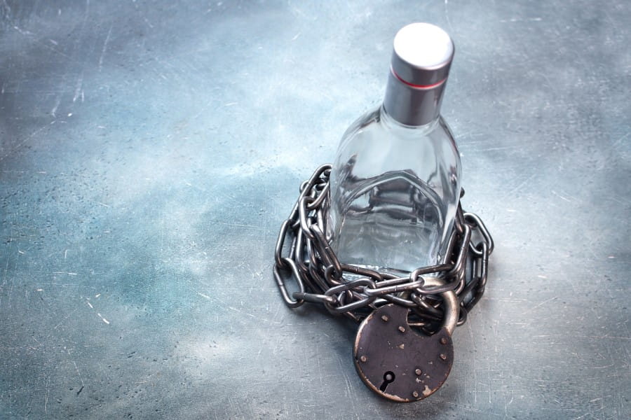 Butelka z mocnym alkoholem, owinięta łańcuchem zamykanym na kłódkę.