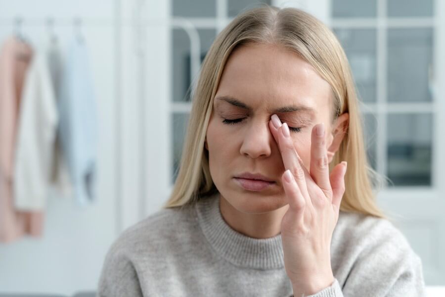 Kobieta pociera dłonią powiekę, cierpi na zespół suchego oka.