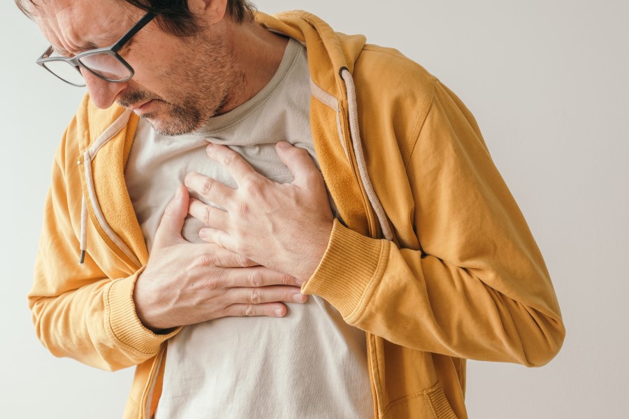 Mężczyzna odczuwa ból w klatce piersiowej, ma ręce ułożone w okolicy serca.