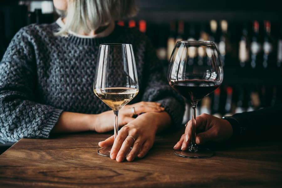 Kobiety w winiarni piją białe i czerwone wino z wysokich kieliszków.
