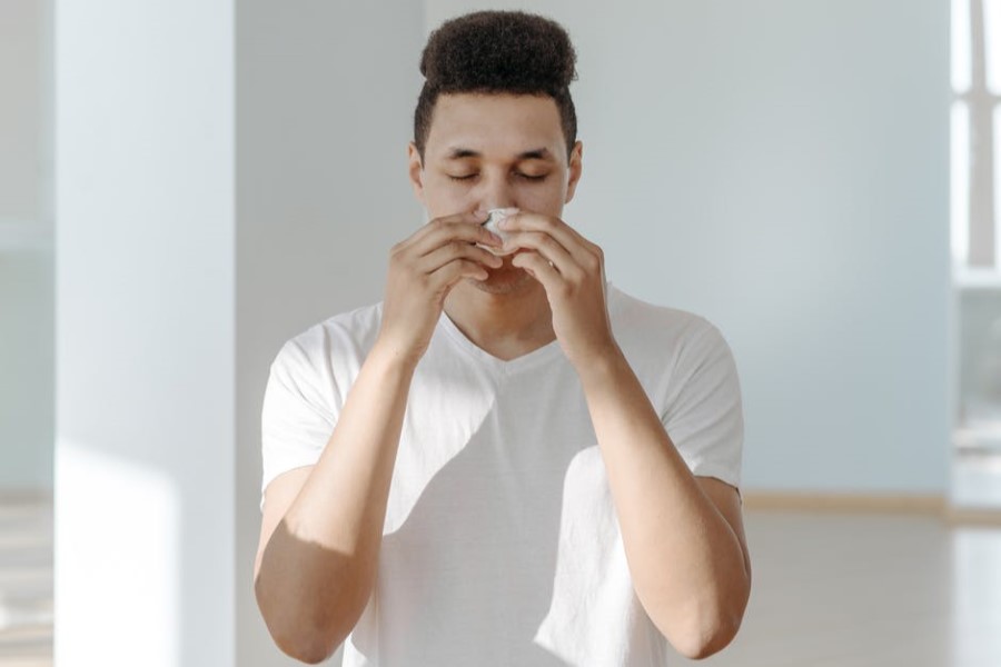 Mężczyzna wydmuchuje nos, ma katar infekcyjny lub katar alergiczny.
