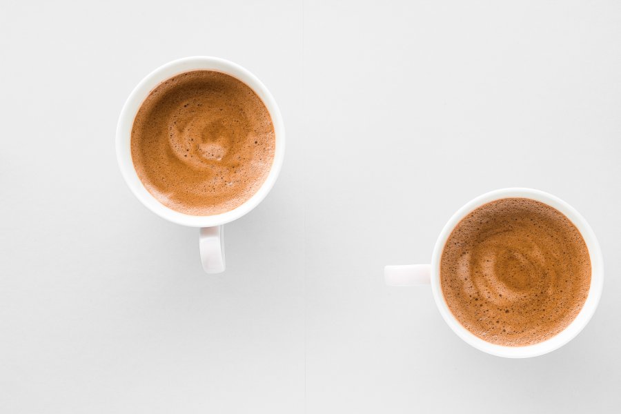 Dwa białe kubki z kawą bezkofeinową leżą na blacie kuchennym