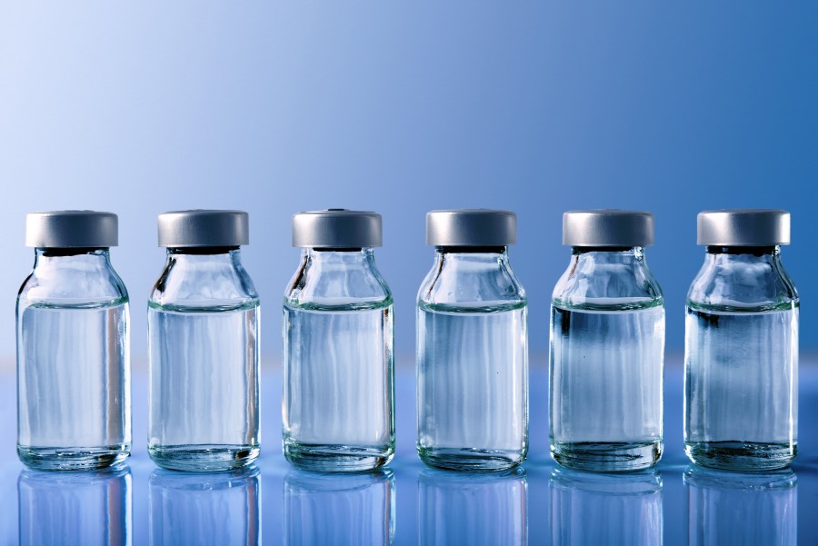 Niebieskie tło, szklane fioli z nakrętką zawierające lek w formie płynnej.
