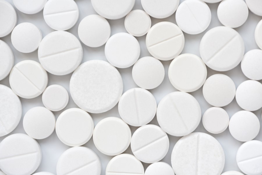Białe tabletki o różnej średnicy, niektóre z nacięciem.